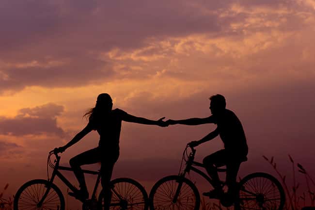 Un beau couple faisant du vélo au coucher du soleil.